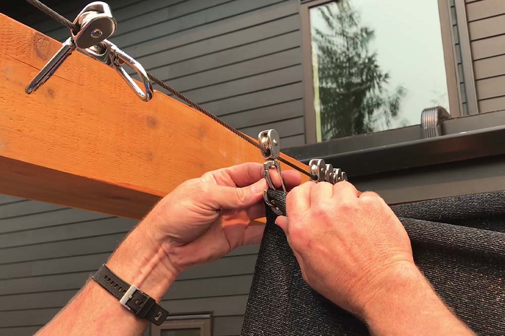 close up of two hands working on installing a shade sail for employee comfort