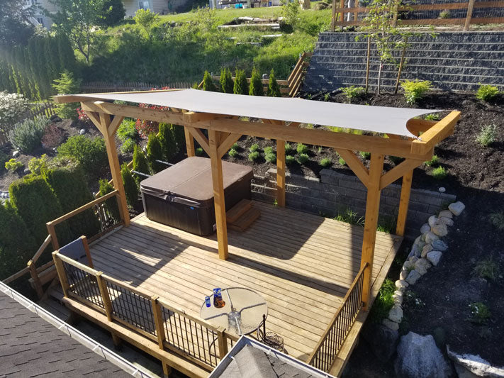 shade cloth over a pergola protecting the hot tub and deck below it from the sun.