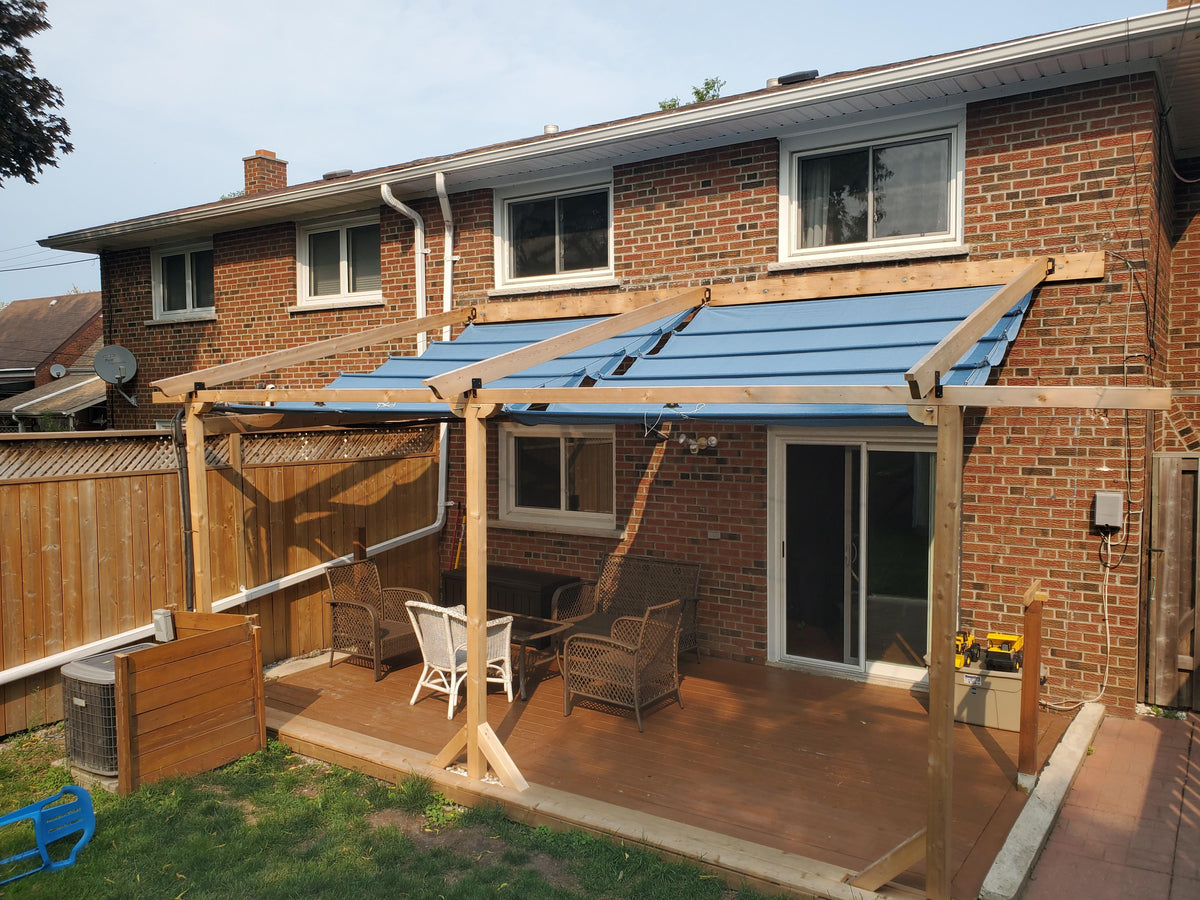 Image of a house with a blue pergola canopy covering the back deck. The blue canopy complements the exterior of the house, adding a touch of elegance to the outdoor space.