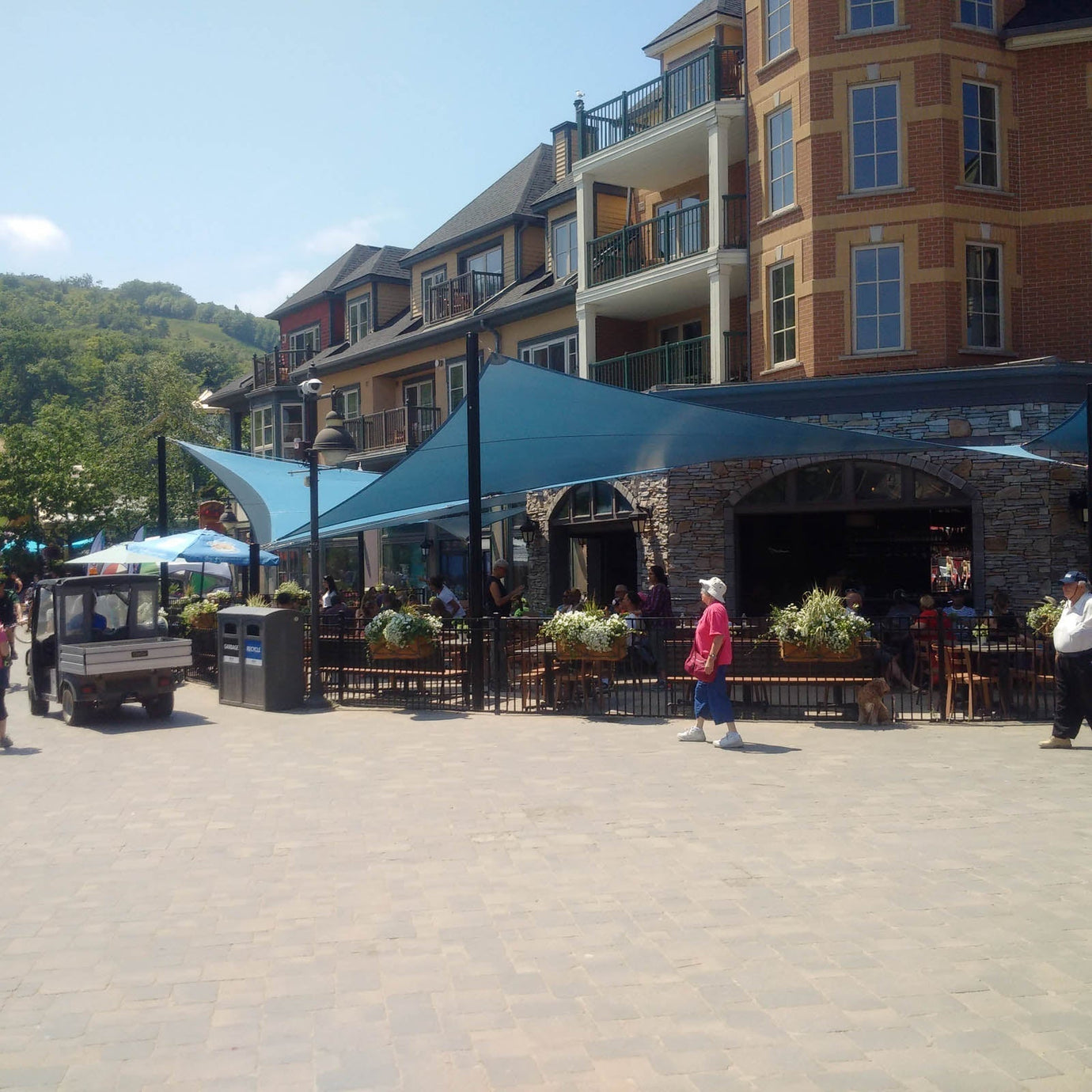blue shade sails over a large commercial patio in a downtown area