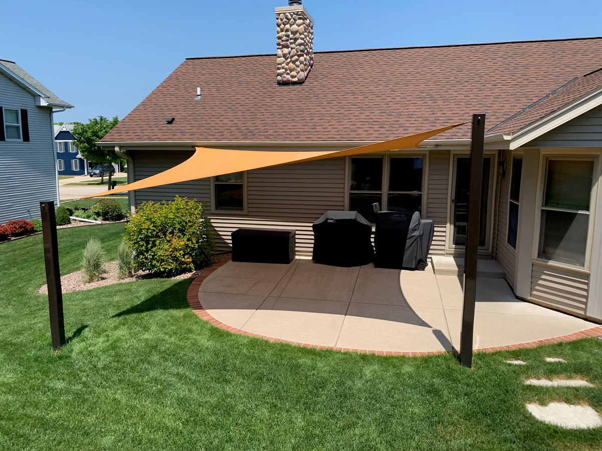backyard with orange shade sail showcasing shade sail posts