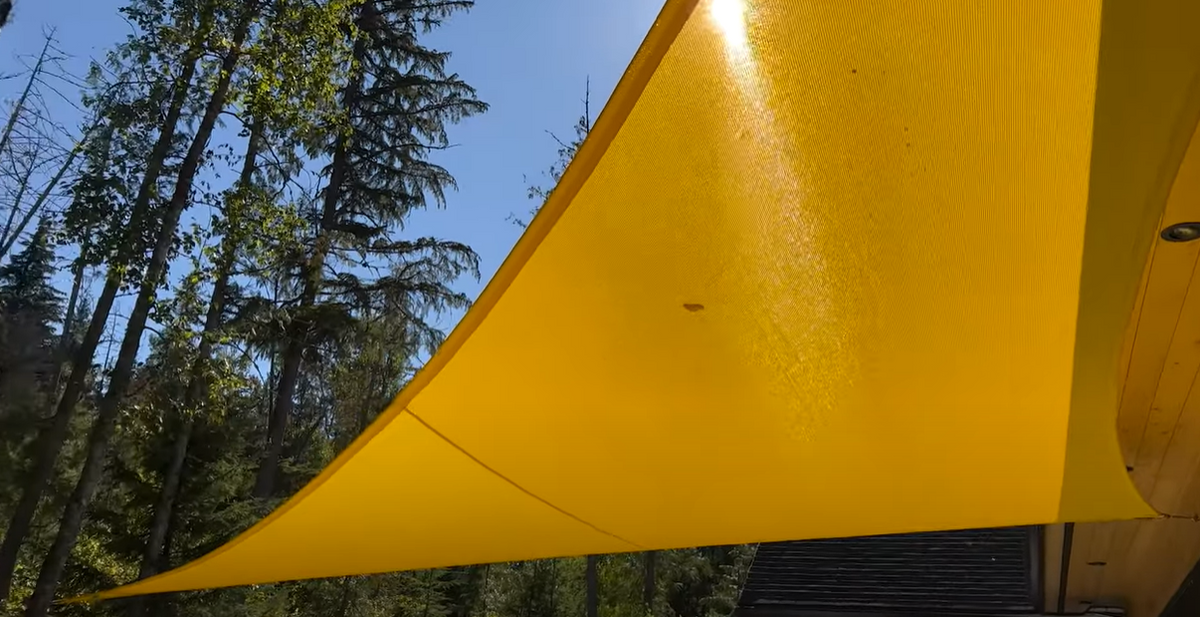 close up image of yellow shade sail attached to a tree showcasing DIY shade sail setup